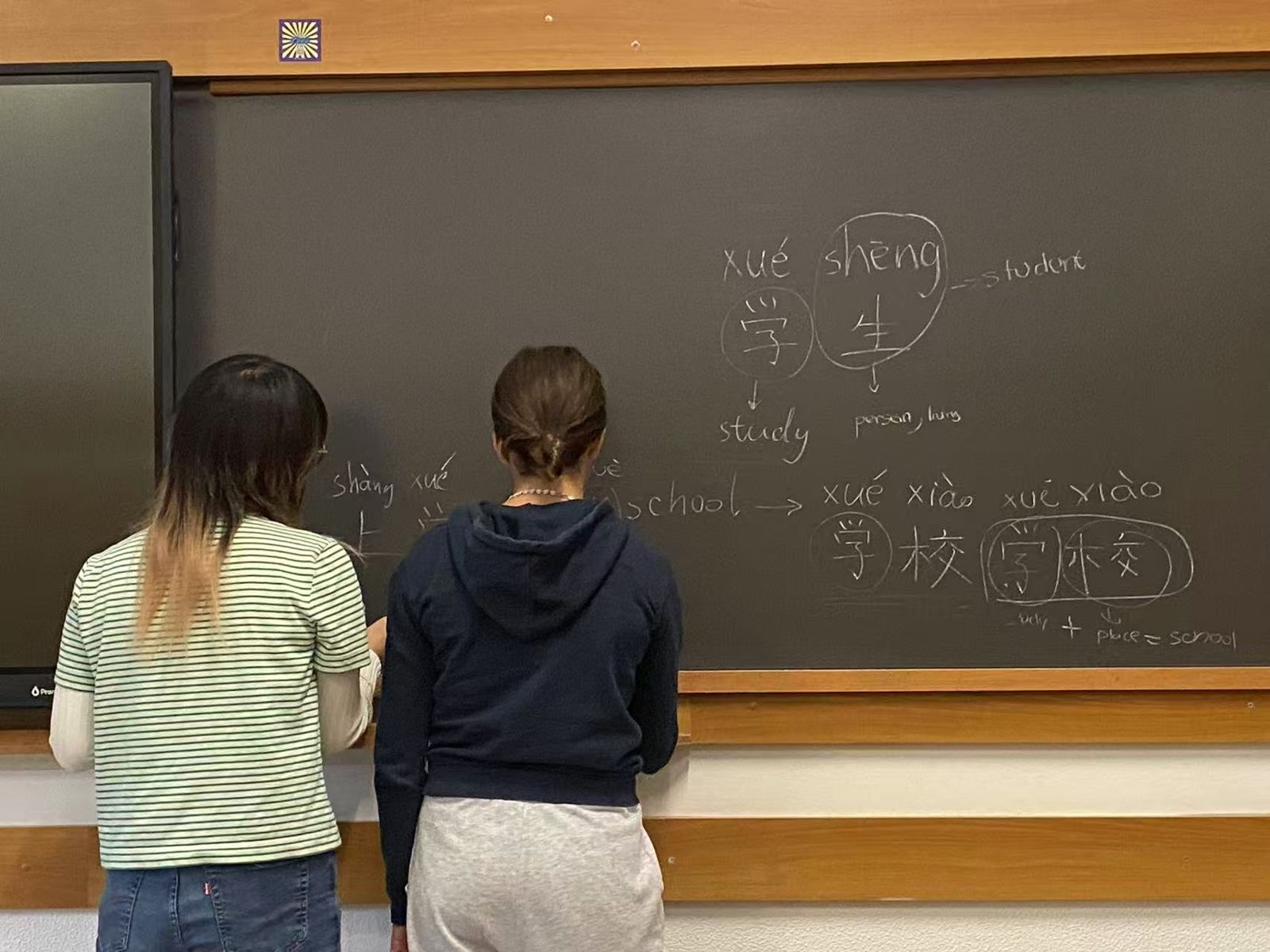 Two students writing Chinese characters at the blackboard, Istituto Leone XIII